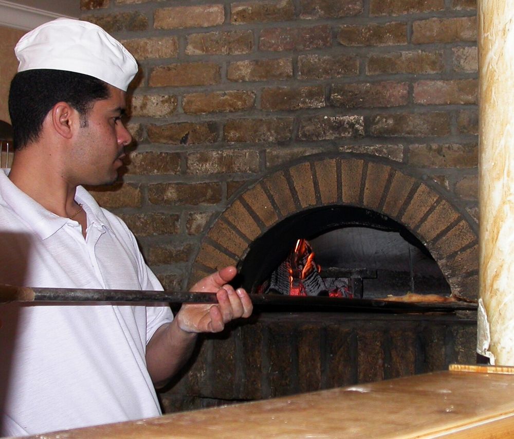 Pizzaiolo colocando a pizza no forno